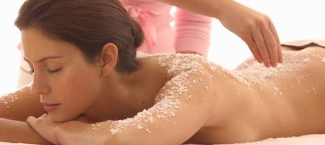 Woman receiving a salt body scrub on a spa table